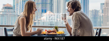 Loving couple having breakfast on the balcony. Breakfast table with coffee fruit and bread croisant on a balcony against the backdrop of the big city Stock Photo
