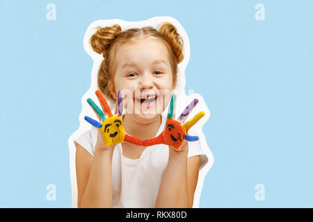 Cheerful little girl child shows hands painted with paint. Blue background, portrait