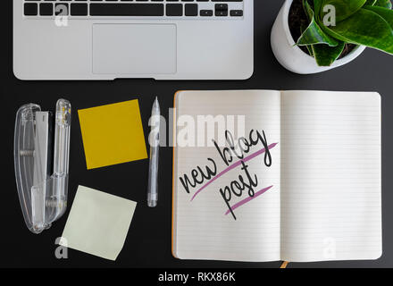 words new blog post written on note pad on desk next to laptop and adhesive notes Stock Photo