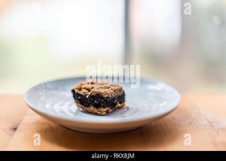Closeup cut golden baked or raw poppy seed bar cake piece slice or chocolate bread filling on table white plate by window Stock Photo