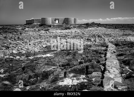 An Infrared monochrome image of Fort Houmet Herbe and causeway on an offshore island on the coast of Aldernney, Channel Islands. Stock Photo