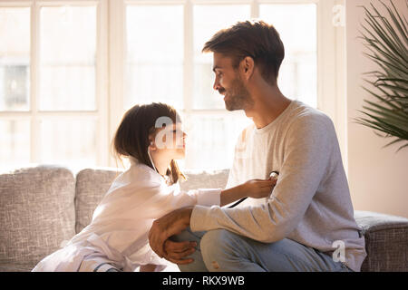 Little daughter playing game as doctor having fun with dad Stock Photo