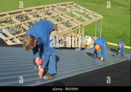 builders working on the roof of a large house Stock Photo