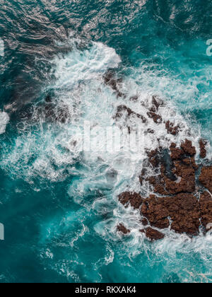 Aerial top view of rocks and sea waves in a volcanic landscape with ...