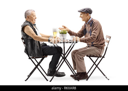 Full length profile shot of a mature punker drinking beer at a table and talking with an elderly man drinking coffee isolated on white background Stock Photo