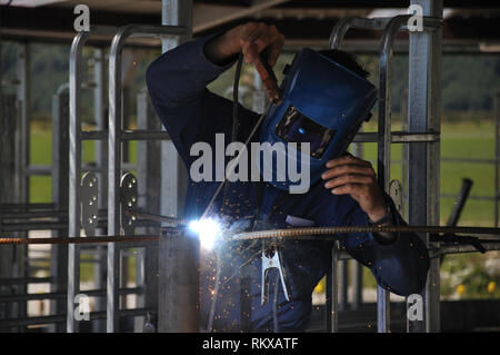 Man spot welding temporary framework in new dairy Stock Photo