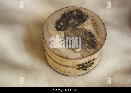 old wooden jewelry box on an old white cloth, close view Stock Photo