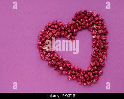 Red heart shape made from popcorn on a pink background Stock Photo