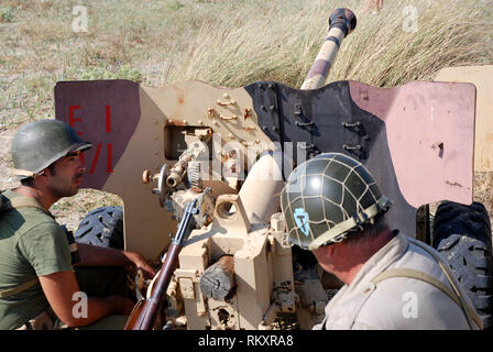 second world war us soldiers near italian anti-tank cannon deployed on the beach of paestum during historical re-enactment of salerno landing 1943 Stock Photo