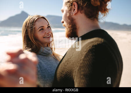 Beautiful woman with her boyfriend at the beach dancing. Couple in love having a lovely movement on sea shore. Stock Photo