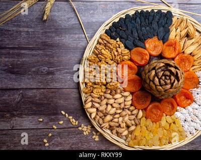 mix of nuts as walnuts, almond, cedar, pistachios, and dried apricots, raisin on wooden background, with copy space, health snack concept, good for he Stock Photo