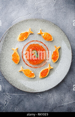 Delicious puff pastry tartlets in the shape of fish with red caviar on a festive table. Stock Photo