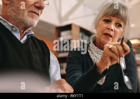 Cropped shot of a senior man and woman learning courses sitting in classroom. Close up of an elderly woman explaining concept to her male colleague. Stock Photo