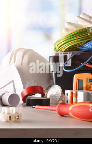 Electrician's office table with electrical equipment and installation drawings with a window in the background. Vertical composition. Front view. Stock Photo