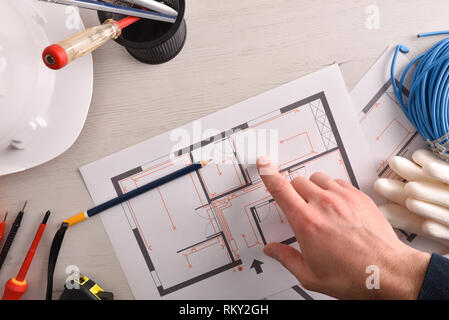Technical electrician preparing an electrical project of housing in the work table. Horizontal composition. Top view. Stock Photo