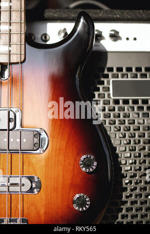 Playing guitar...Close up photo of a brown electric guitar with volume and tone control knobs and amplifier standing in audio recording studio. Music recording. Music equipment. Musical instruments. Stock Photo