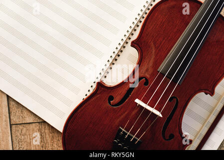 Writing Violin Music. Close up view of beautiful brown violin lying on sheets for music notes. Violin lessons. Musical instruments. Music equipment. Stock Photo