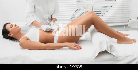 Beautiful woman having cavitation , cellulite treatment, on her abdomen at beauty clinic Stock Photo