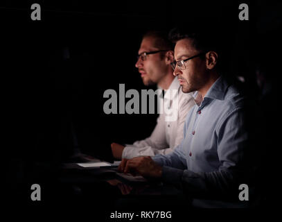 two colleagues sitting at the Desk.isolated on black Stock Photo