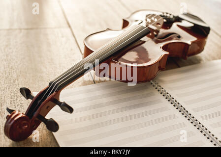 Visual beauty of classical instrument. Close up view of brown beautiful violin lying on sheets for music notes over wooden floor. Musical instruments. Music equipment. Music background Stock Photo