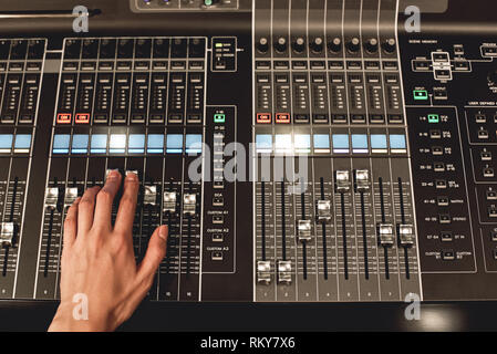 Professional sound control. Close-up view of male hand mixing sounds on digital audio mixing console. Media production. Media production studio. Music record service Stock Photo