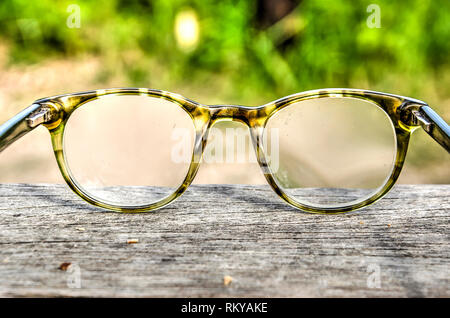 Reading glasses in a plastic frame on a rough wooden surface against a grain background Stock Photo