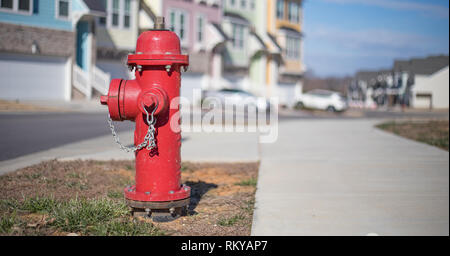 Bokeh shot of a bright red fire hydrant on a community street with a row of townhouses behind it. Stock Photo