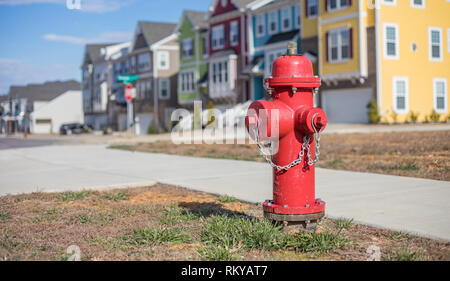 Bokeh shot of a bright red fire hydrant on a community street with a row of townhouses behind it. Stock Photo