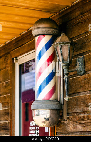 Classic barber pole sign outside barber shop in Lawrenceburg in Kentucky.