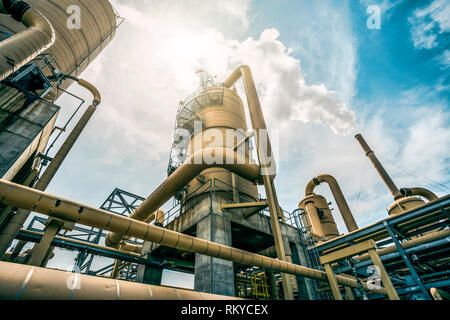 Looking up towards the sky surrounded by the tanks and tubes of a geothermal power plant releasing steam in Calipatria in California. Stock Photo