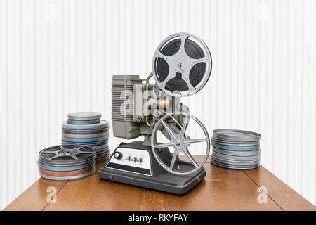 Vintage 8mm home movie projector and film cans on wood table. Stock Photo