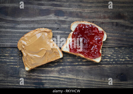 Top view of open face homemade peanut butter and strawberry Jelly sandwich on oat bread, over a rustic wooden background. Stock Photo