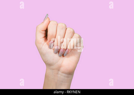Closeup view of beautiful female hands with old silver sparkling manicure isolated on pink background. Woman needs correction. Horizontal color photog Stock Photo
