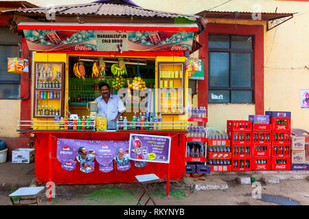 Man selling soft drinks from a brightly coloured street stall in India. Stock Photo