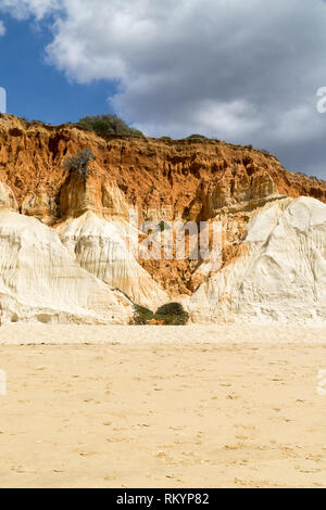 High cliffs along Falesia Beach and The Atlantic Ocean in Albufeira, Algarve, Portugal. Sunny summer day, blue sky with stormy clouds. Stock Photo