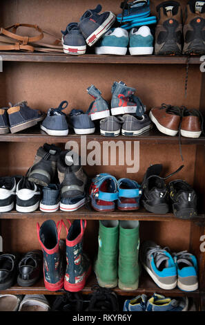 Childrens shoes stored in an old oak bookcase UK Stock Photo