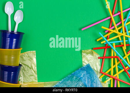 No plastic concept. Single use plastic cups, spoons, bags, drinking straws on green background Stock Photo