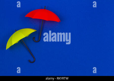 Small colorful umbrellas on blue color background Stock Photo