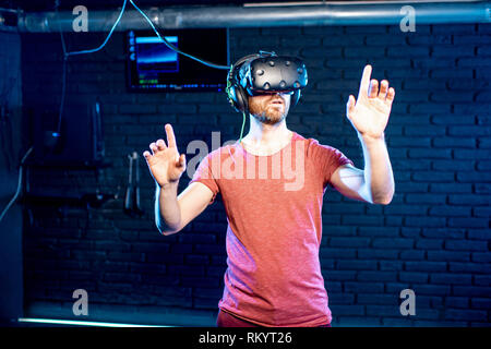 Man touching virtual reality space using VR headset in the playing room Stock Photo