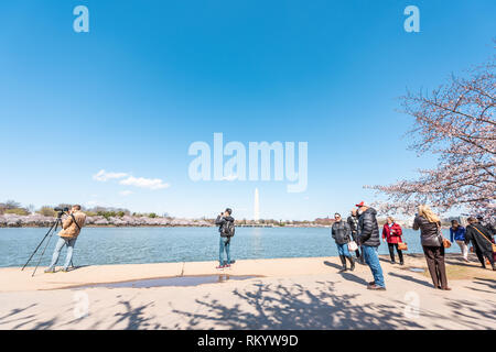 Washington DC, USA - April 5, 2018: Tourists people and famous monument at Tidal Basin lake pond with cherry blossom sakura trees in spring at Nationa Stock Photo