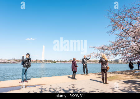 Washington DC, USA - April 5, 2018: Tourists people and monument at Tidal Basin lake pond with cherry blossom sakura trees in spring at National mall Stock Photo