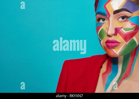 Stylish woman looking at camera, posing. Confident and charming model has creative, colorful pop art make up, pink plump lips. Studio with blue background. Stock Photo