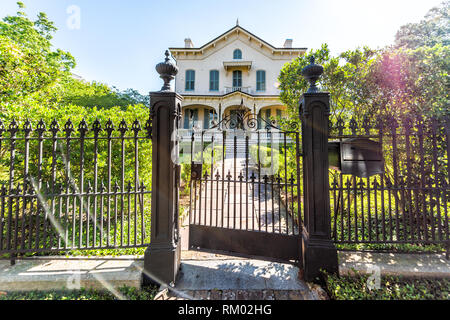 New Orleans, USA - April 23, 2018: Old historic Garden district in Louisiana famous town city with real estate historic house and green lawn with gate Stock Photo