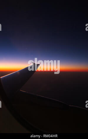 Vision of an evening from the cockpit of an airplane from which the wing of the passenger plane itself can be seen Stock Photo