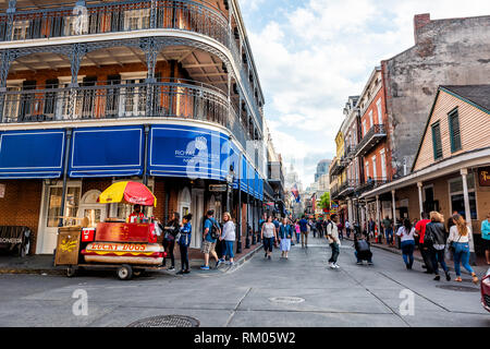 New Orleans, USA - April 23, 2018: Od town Bourbon street road Louisiana famous town city and Royal Sonesta hotel blue banner on cast iron balcony Stock Photo