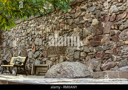 A wall assembled from preserved medieval fragments of stone crosses, carved ornaments and facade details on the territory of the Gegard Monastery of A Stock Photo