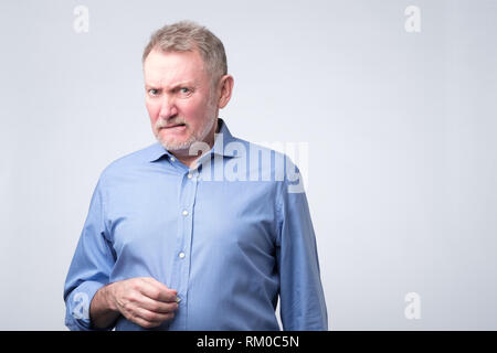 Senior man in blue shirt looking with disbelief expression . Stock Photo