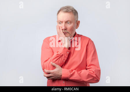 Senior man in red shirt thinking about his life problems. Stock Photo