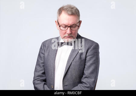 Senior businessman in suit and glasses looking down Stock Photo