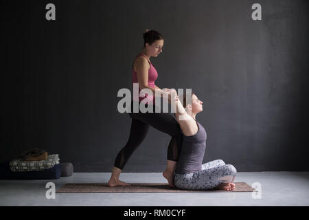 woman helping her friend to open shoulders and chest doing yoga asana, Stock Photo